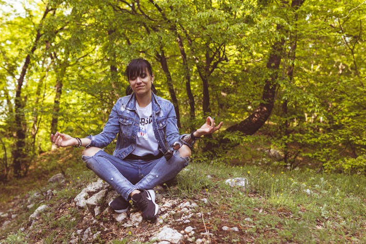 Woman Meditating While Sitting On Rocks