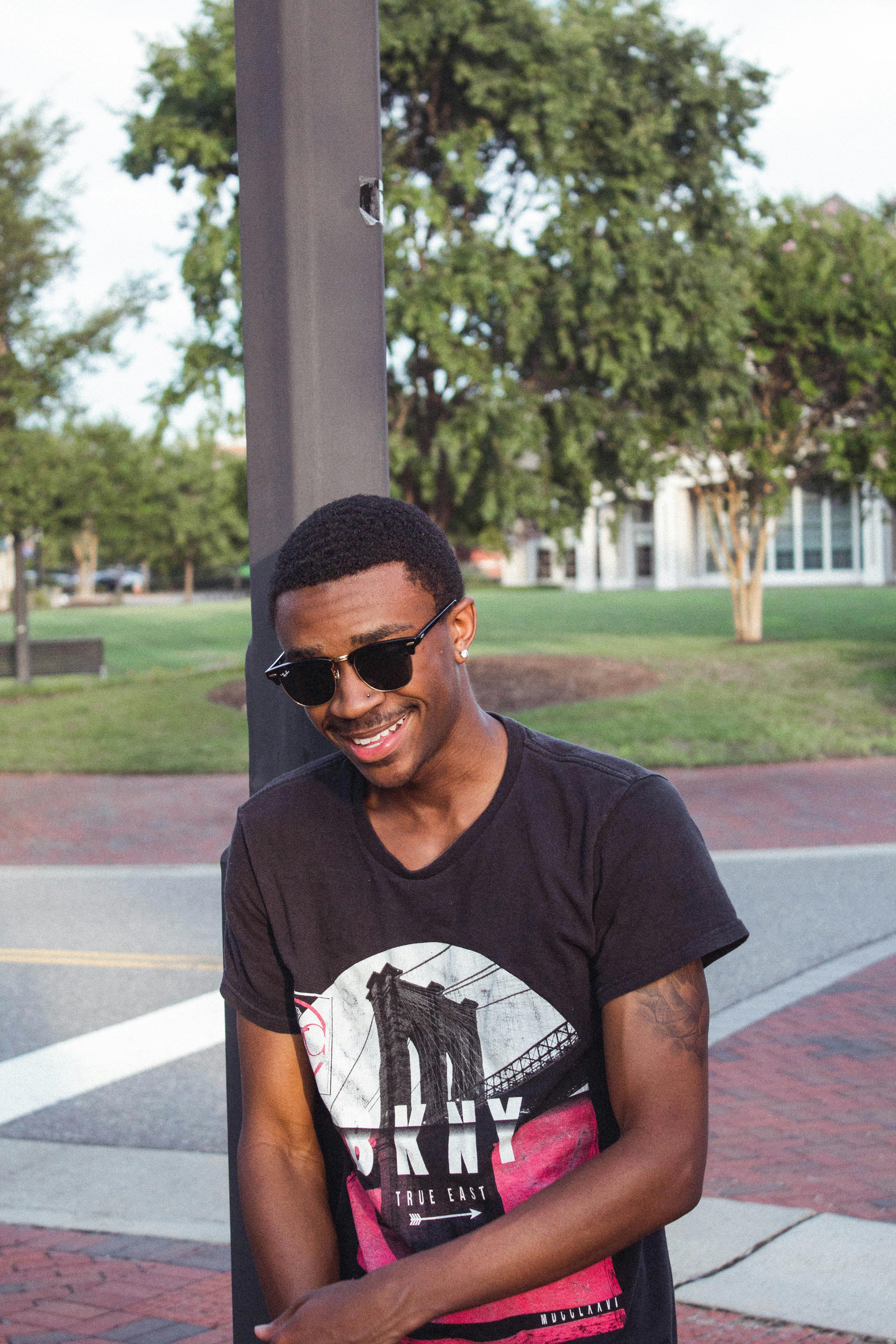 在弗吉尼亚州威廉斯堡的公园里，一位戴着墨镜的休闲年轻人微笑着