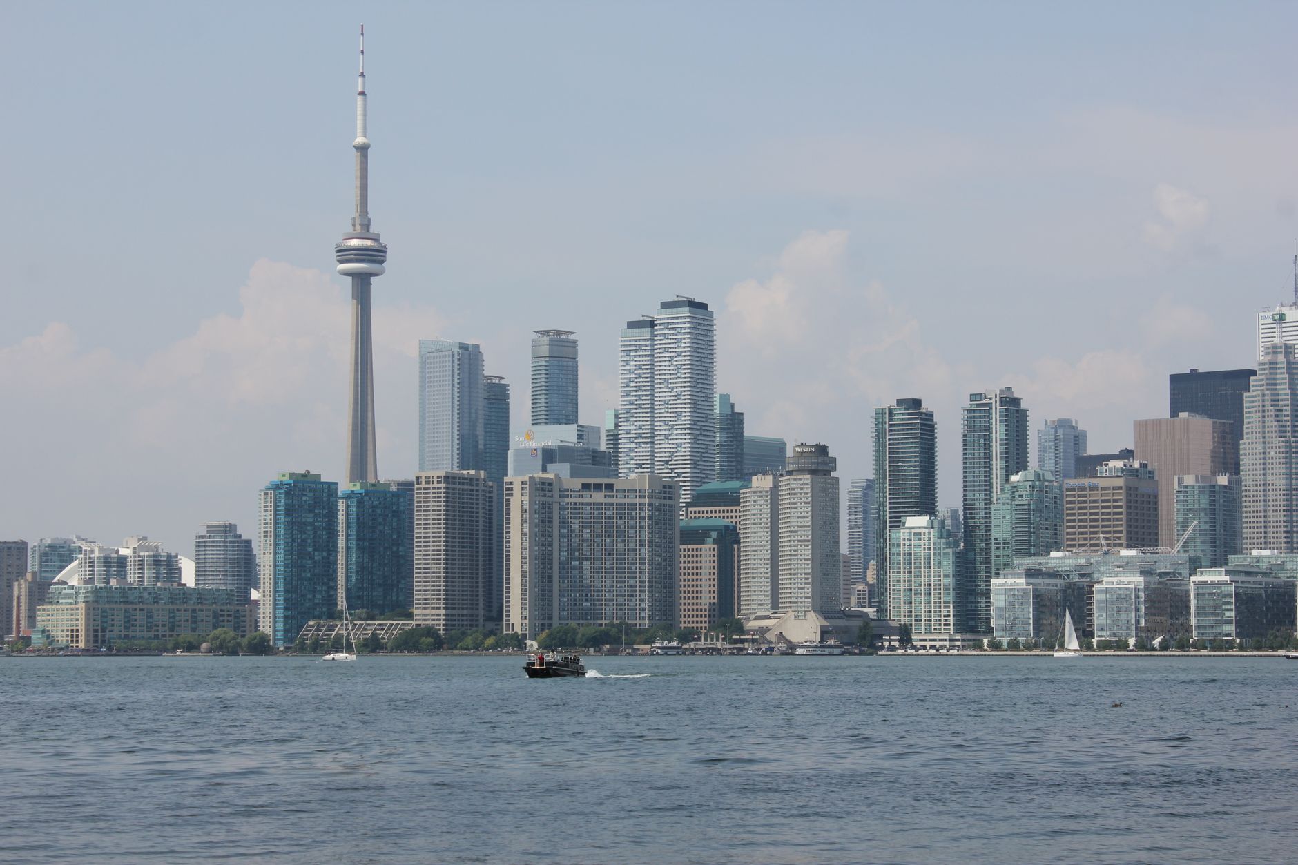 Scenic view of Toronto skyline with CN Tower over Lake Ontario under clear skies.