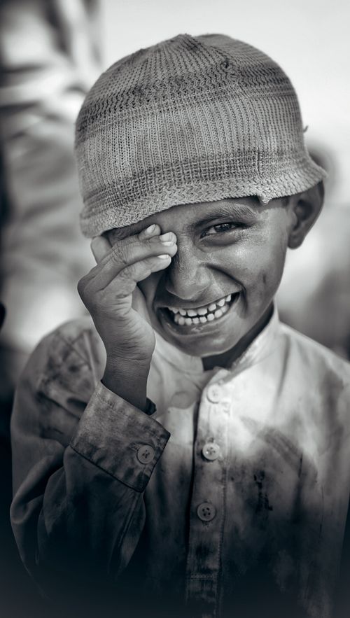 Free Captivating black-and-white portrait of a young boy smiling joyfully, wearing a beanie. Stock Photo