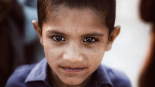 Free Intimate close-up portrait capturing the innocence and deep gaze of a young boy outdoors. Stock Photo