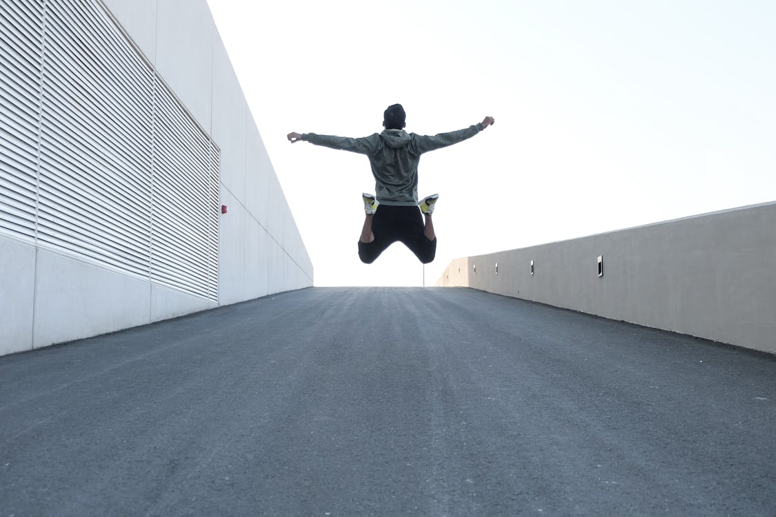 Man in Gray Hoodie Jump With Open Arms