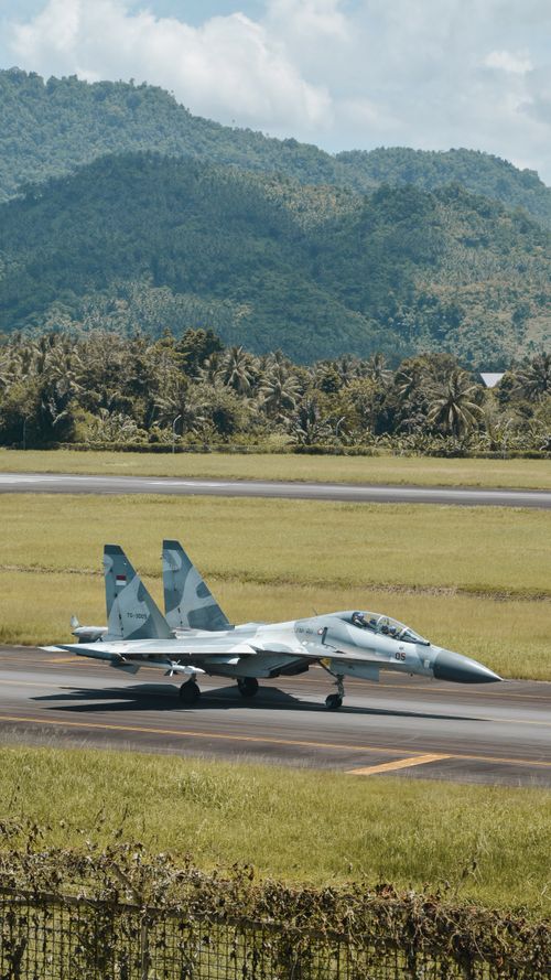 Free Sukhoi Su-30 fighter jet on a runway with mountain backdrop in Manado, Indonesia. Stock Photo