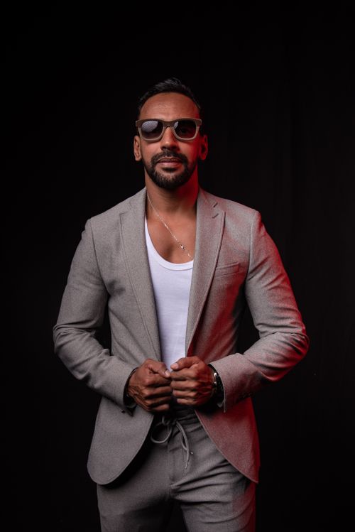 Free Portrait of a confident man wearing a gray suit and sunglasses against a black background. Stock Photo