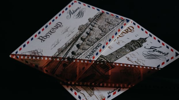 Artistic close-up of vintage postcards from Adana and Izmir under a photographic film strip.