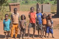 A cheerful group of children pose outdoors in Blantyre, Malawi, on a sunny day.