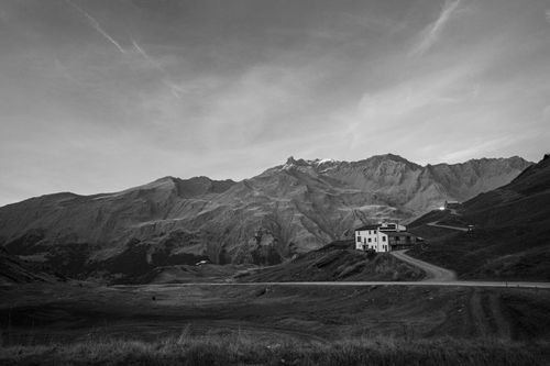 Free A solitary house nestled in a vast mountain landscape under a wide sky. Stock Photo