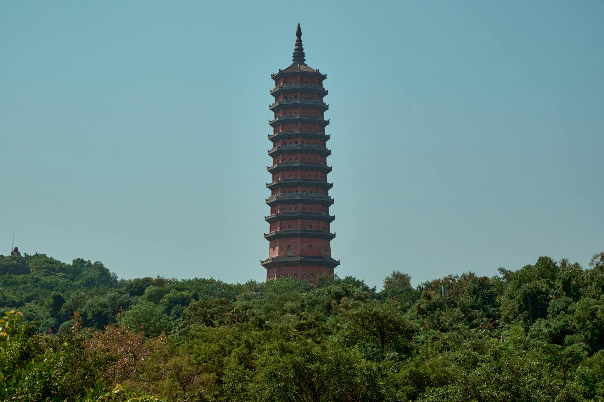 View of the Bai Dinh Pagoda towering above lush green trees in Vietnam, showcasing cultural architecture.