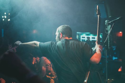 Back view of a guitarist performing at a live concert, engaging with the audience.