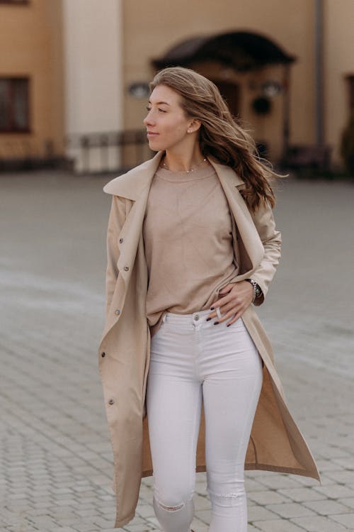 Woman in Brown Coat and White Pants Looking Sideways