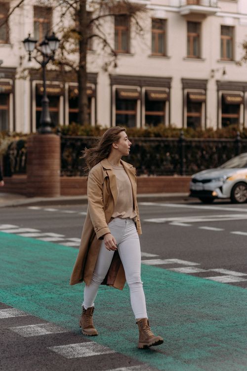 A Woman in Brown Coat and Denim Pants Standing on Road · Free Stock Photo