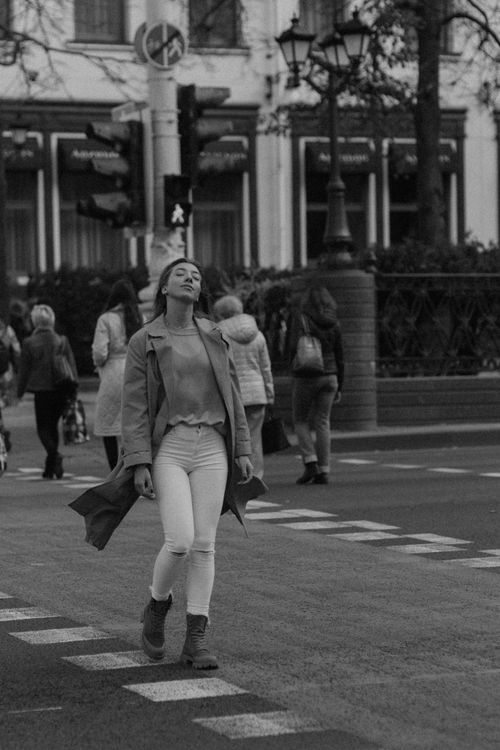 Free A woman walks confidently with eyes closed on a busy city street in grayscale. Urban lifestyle moment. Stock Photo