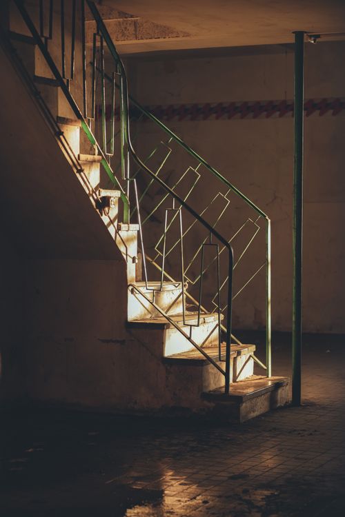 Free A vintage metal-railed staircase in a dimly lit interior space, evoking a moody and nostalgic atmosphere. Stock Photo