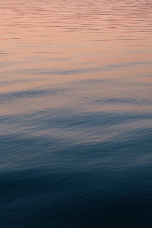 Smooth Water Surface with a Reflection of a Pink Sunset Sky 