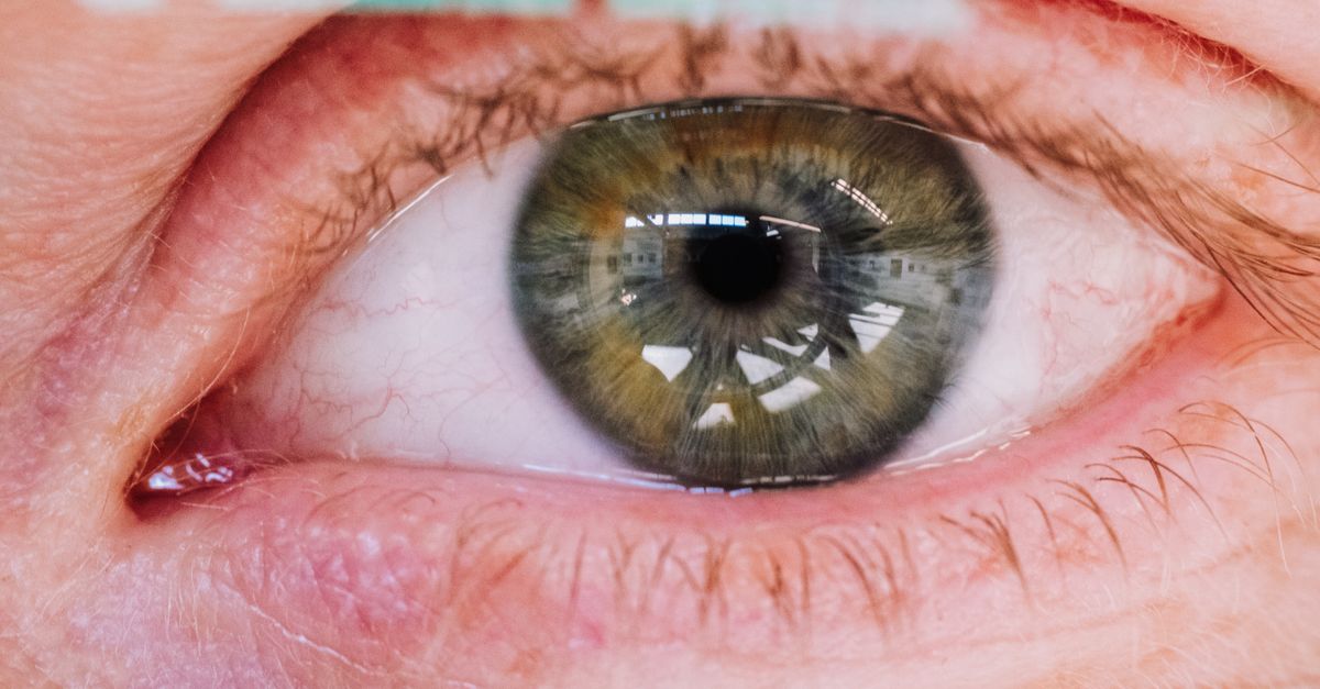 A close-up image of a green human eye with intricate reflections, showcasing vivid detail.
