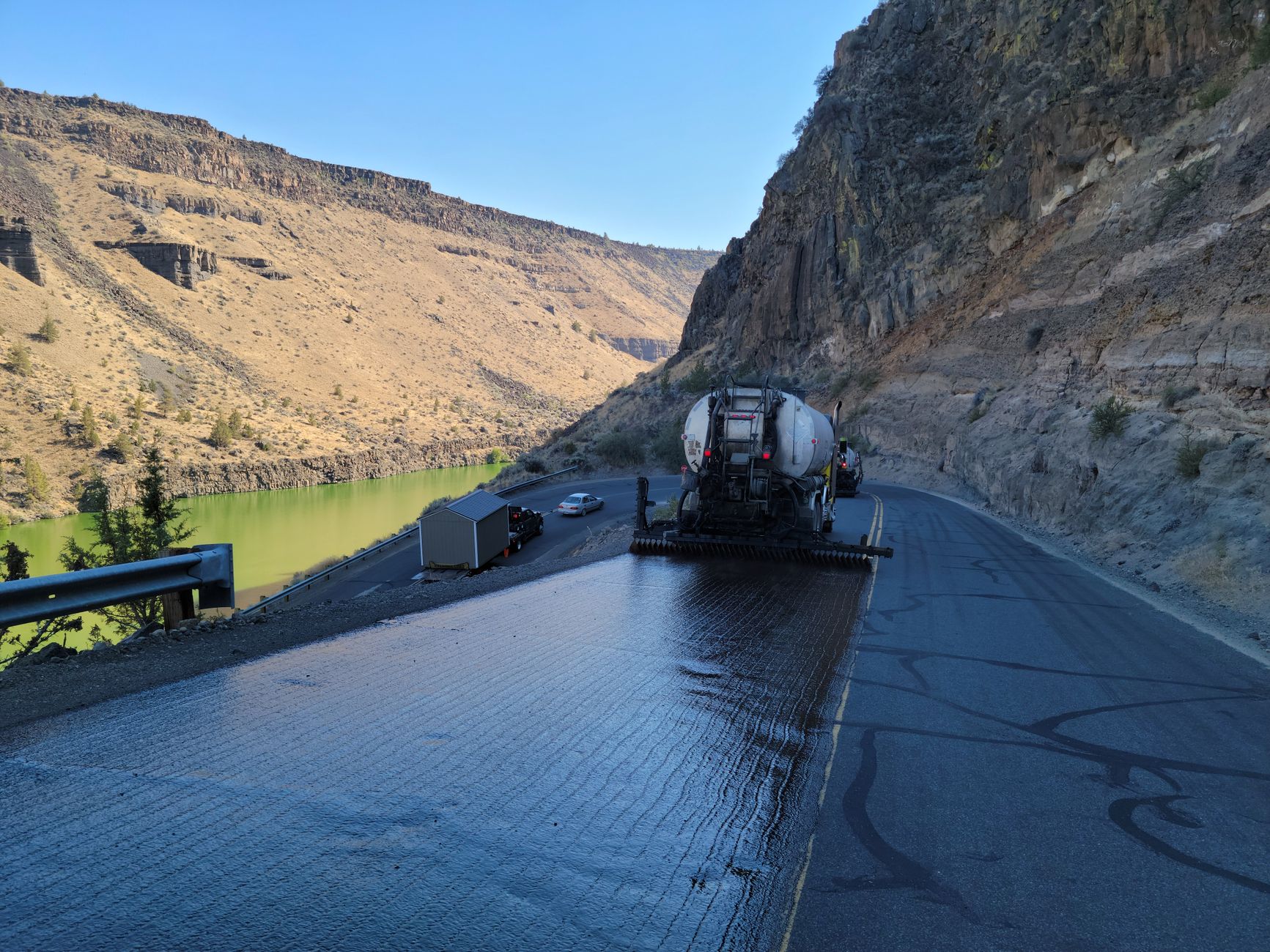 Chip seal truck resurfacing a highway through Terrebonne Gorge, Oregon during daylight.