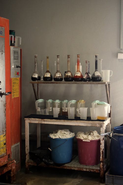 Flasks on Shelf above Table of Plastic Containers 