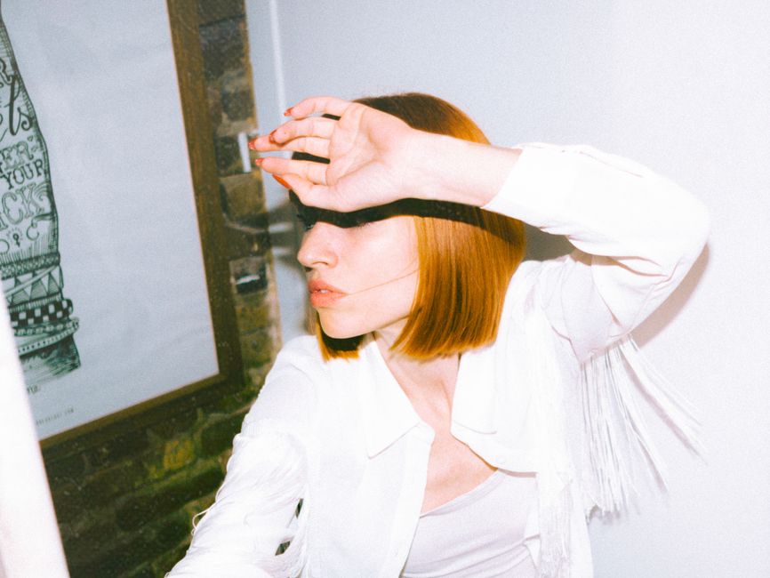 Stylish redhead woman in white outfit posing indoors in Montréal, QC, Canada.
