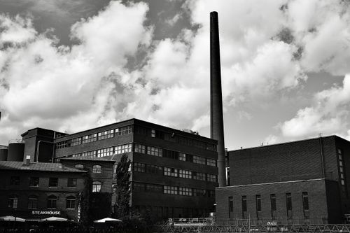 Free Dramatic black and white photo of an industrial factory with a chimney and steakhouse. Stock Photo