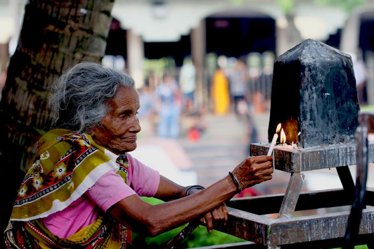 Elderly Woman Lighting A Candle