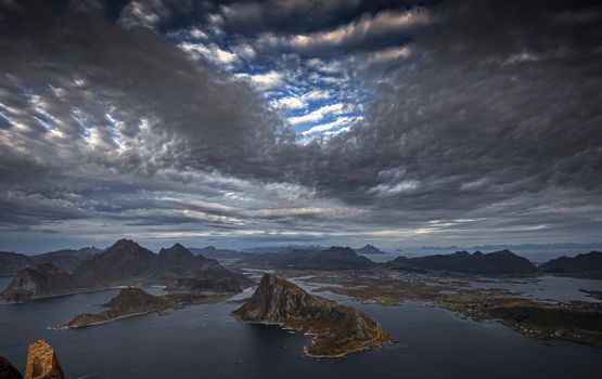 Captivating aerial shot of Lofoten Islands with stormy skies and rugged coastline at dusk.