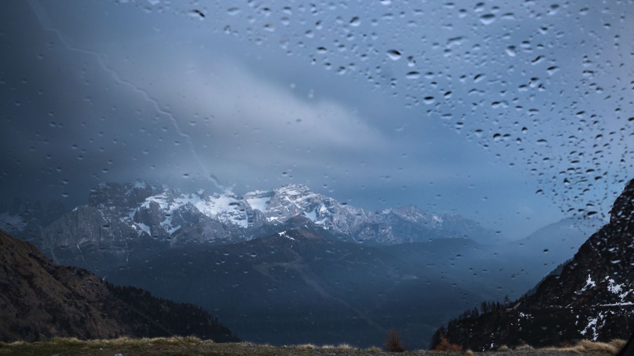 snow capped mountains viewed through a windshield with raindrops creat