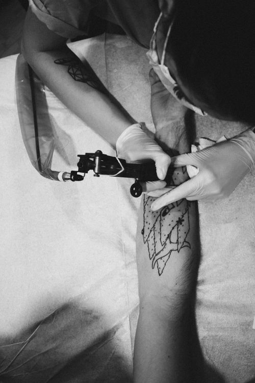 Free A tattoo artist skillfully designs a unique pattern on a client's arm in monochrome. Stock Photo