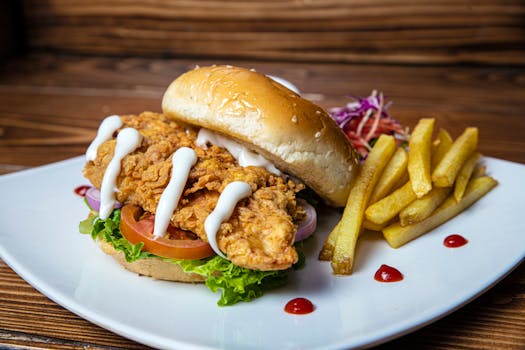Delicious crispy chicken sandwich with fries on a plate, perfect for fast food lovers.
