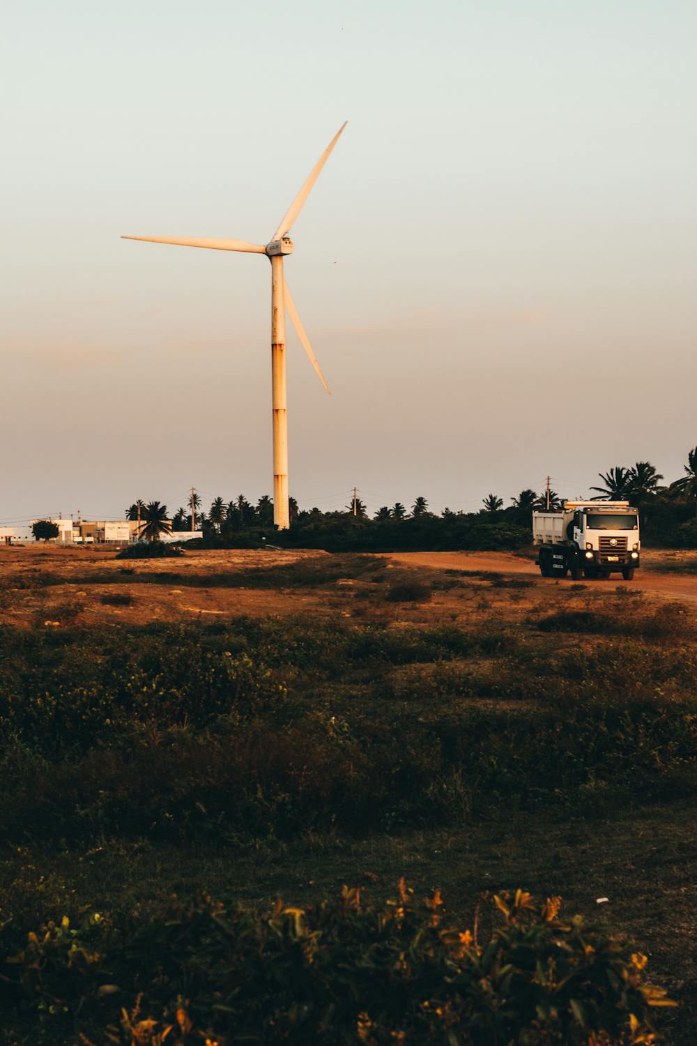 A dump truck drives past a windmill.