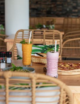 Colorful smoothies and delicious pizza in a cozy cafe setting, perfect for a casual meal.