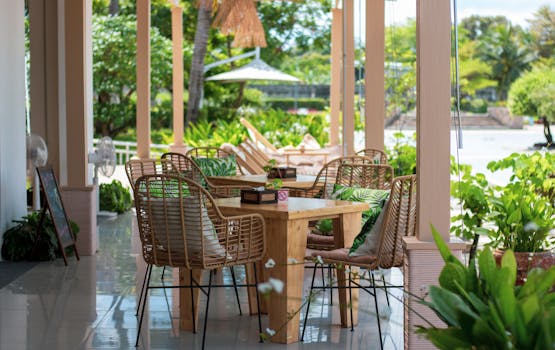 Cozy outdoor café with wooden tables and wicker chairs amidst lush greenery.