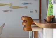 Contemporary kitchen interior featuring a wooden bar stool and decorative wall fish, offering a stylish and cozy ambiance.