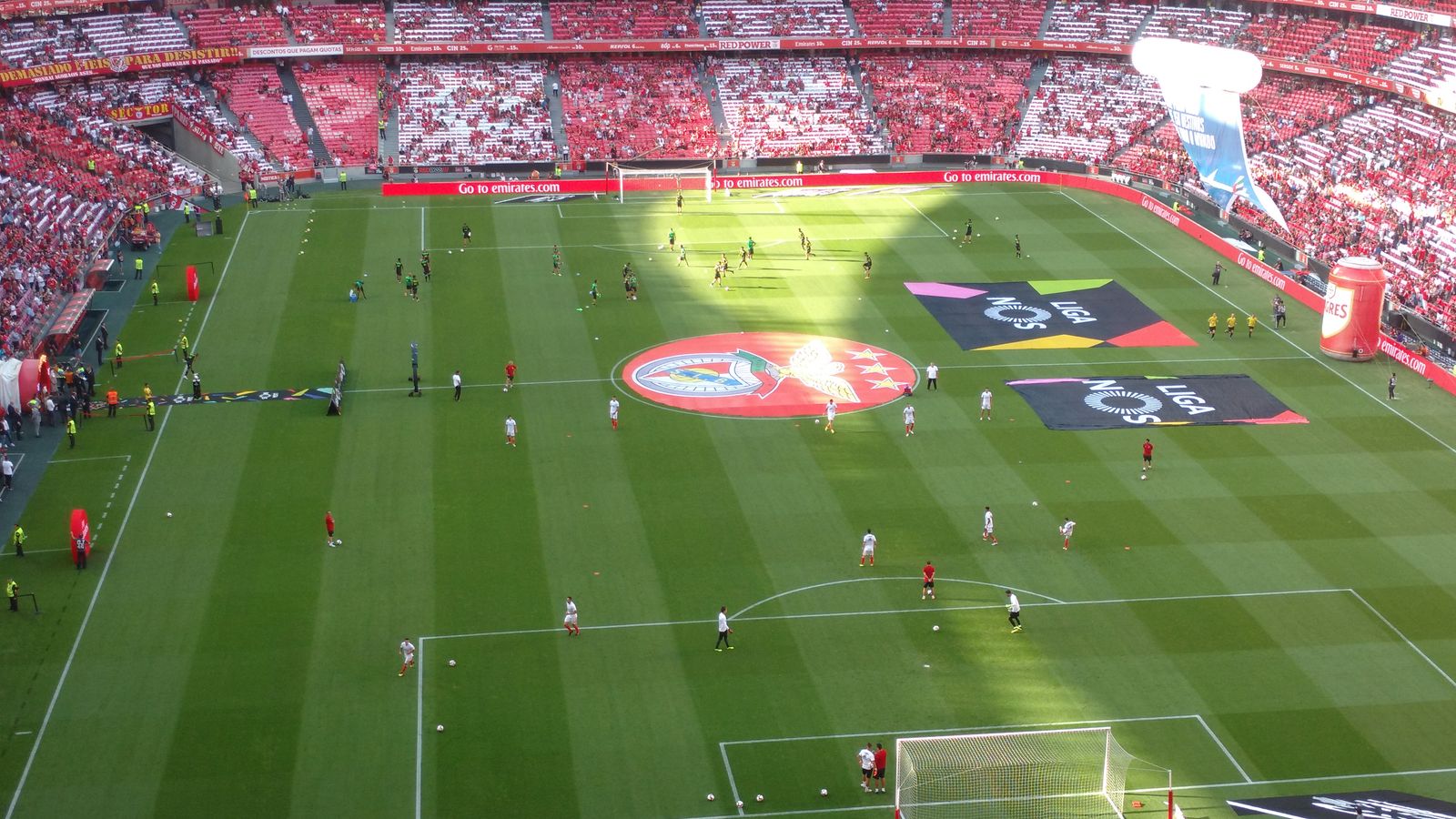Aerial view of a soccer field during a match in a packed stadium with players and fans.