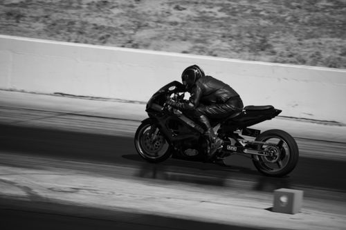 Free Black and white photograph capturing a motorcyclist in action during a high-speed race. Stock Photo