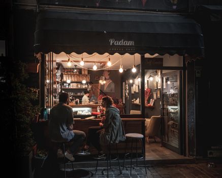 Charming night scene at Padam Coffee Shop with people enjoying a warm atmosphere in Ankara, Turkey.