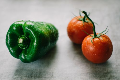 Free Fresh green bell pepper and tomatoes with water droplets, symbolizing organic farming. Stock Photo
