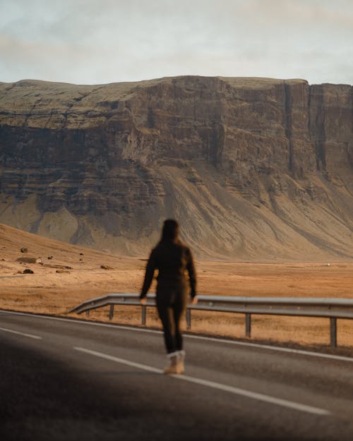 Woman Walking on Road near Rock Formation