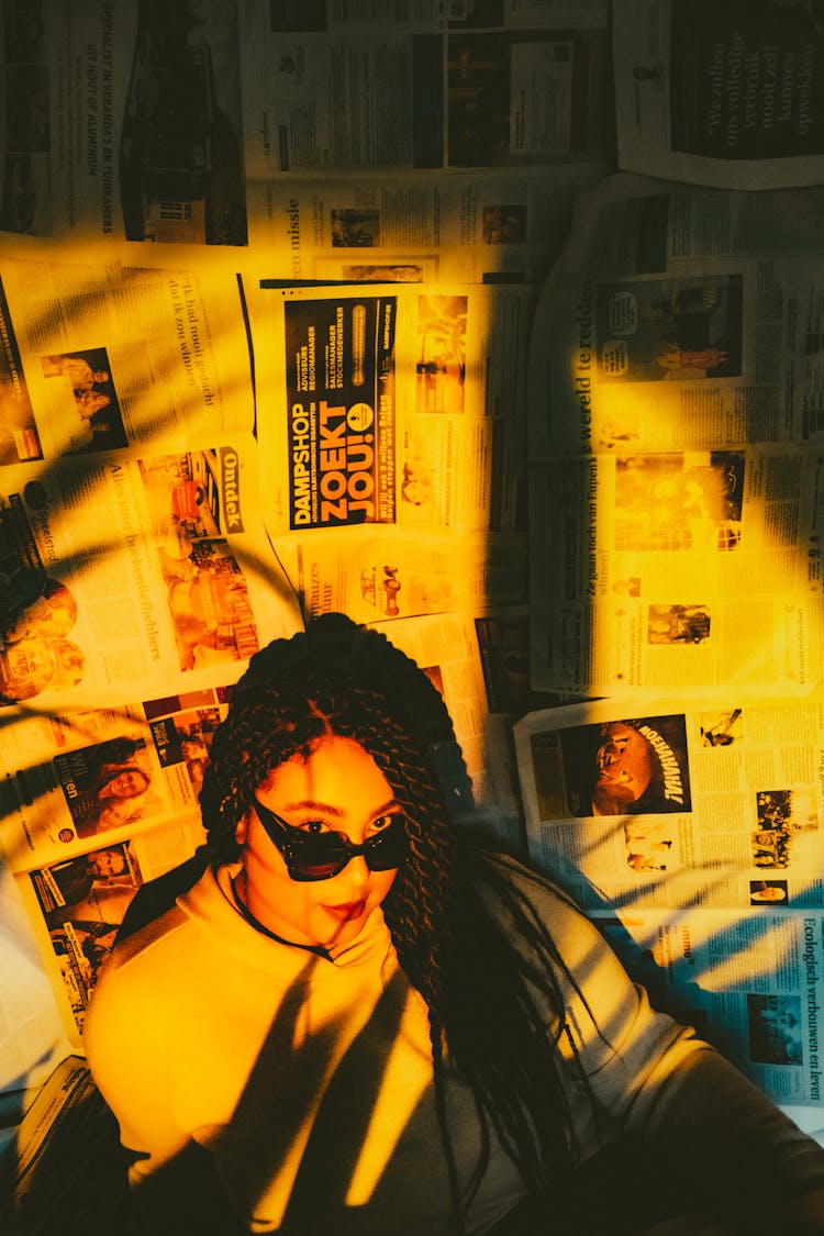 Woman With Dreadlocks Against Wall With Newspaper Pages