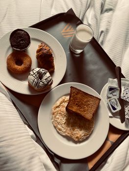Indulge in a breakfast tray featuring fried eggs, toast, pastries, and milk for a cozy start to your day.