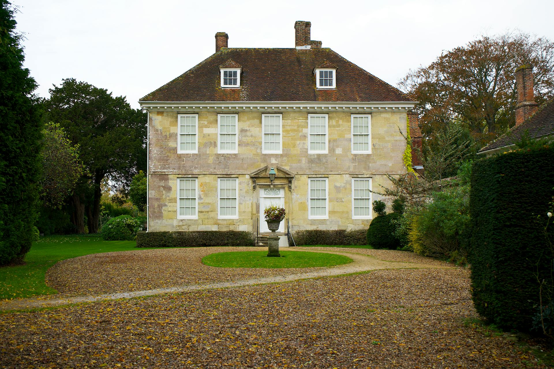 A Yellow and Brown House Near a Garden with Green Trees and Plants