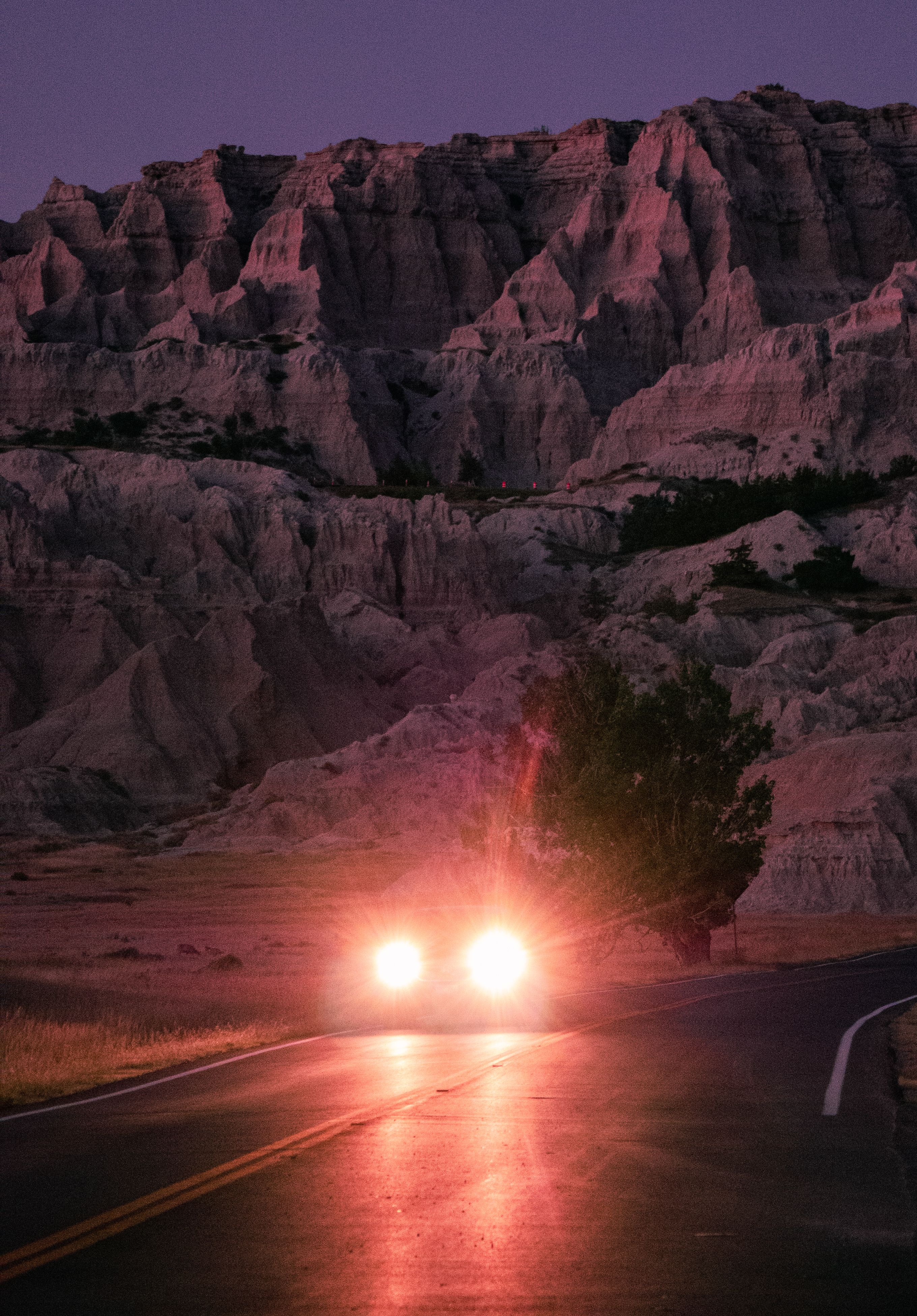 Key art: headlights on a night road below eroded rock formations. Photo by Amaury Michaux on Pexels