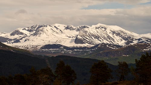 An Aerial Photography of Snow Covered Mountains Under the Cloudy Sky