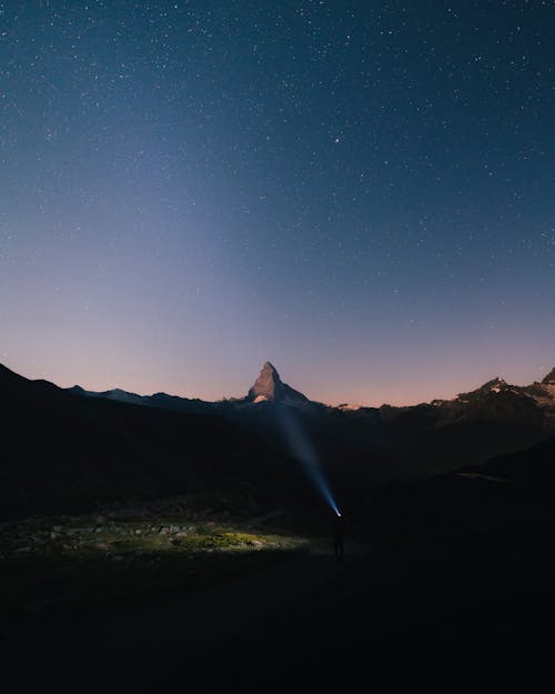 Hiker with Strong Flashlight in the Valley near Matterhorn at Night