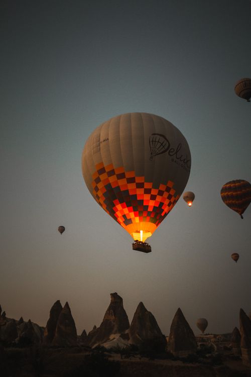 Free Colorful hot air balloons soar over Cappadocia's fairy chimneys at sunset in Turkey. Stock Photo