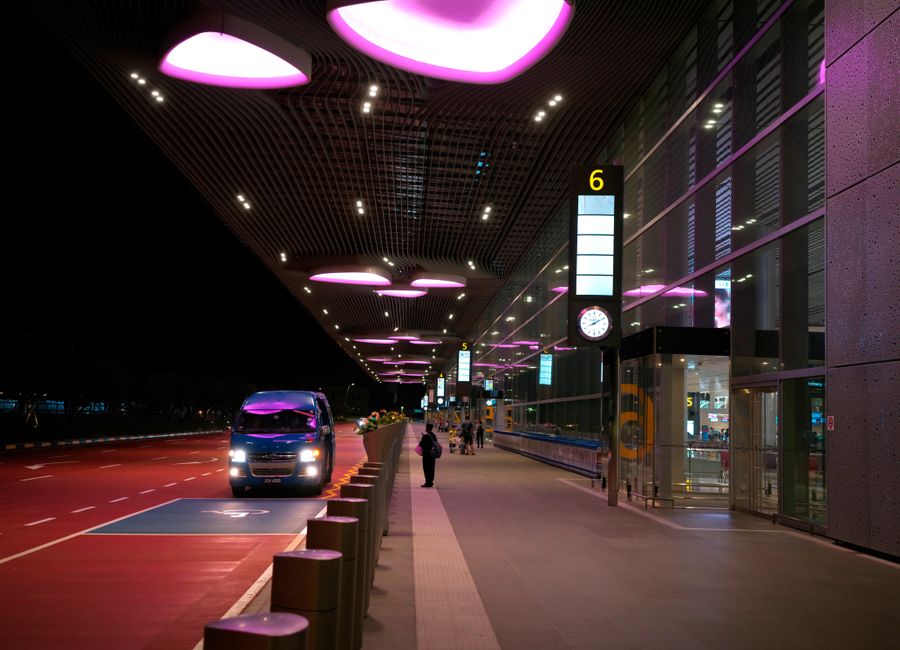 Night view of Singapore's Changi Airport entrance with illuminated canopy and bus.