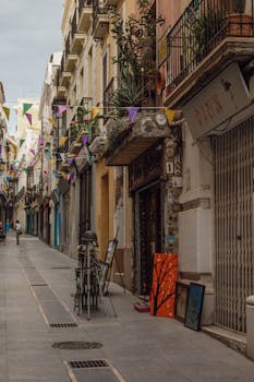 Charming street scene in Badajoz, Spain with cobblestones, flags, and colorful buildings.