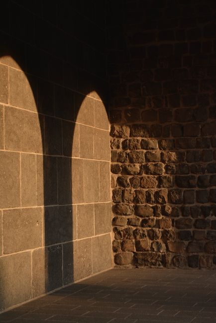 Warm-toned shadow of arches on an ancient brick wall, conveying historic charm.