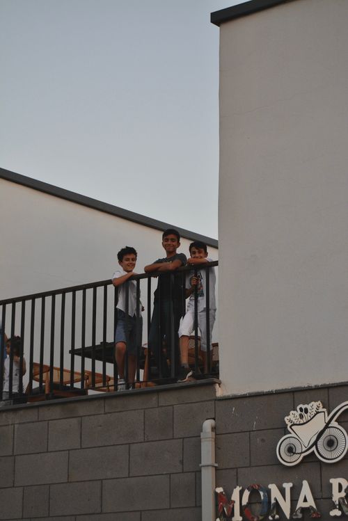 Free Three teenage boys enjoy the view from a rooftop balcony, standing behind a metal railing. Stock Photo