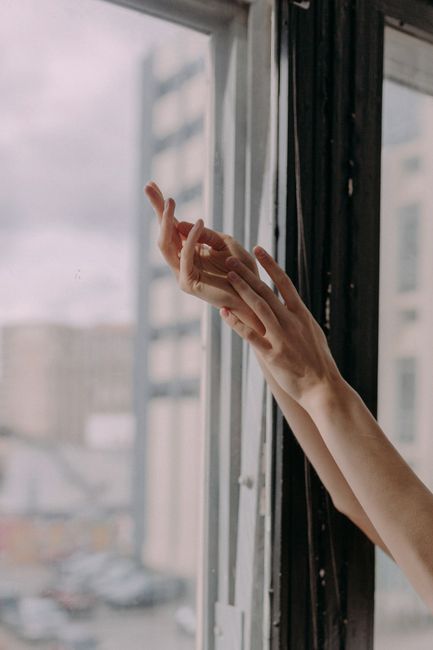 A serene image of graceful hands reaching towards natural window light indoors.