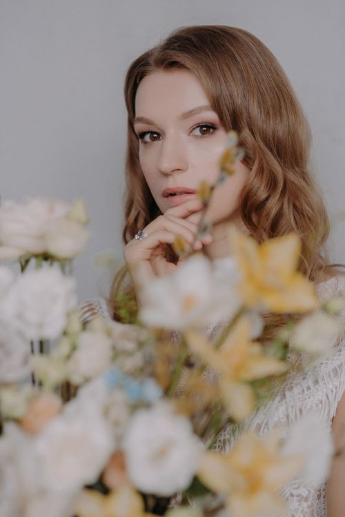 Free A captivating portrait of a woman with brunette hair, softly focused among delicate pastel flowers. Stock Photo